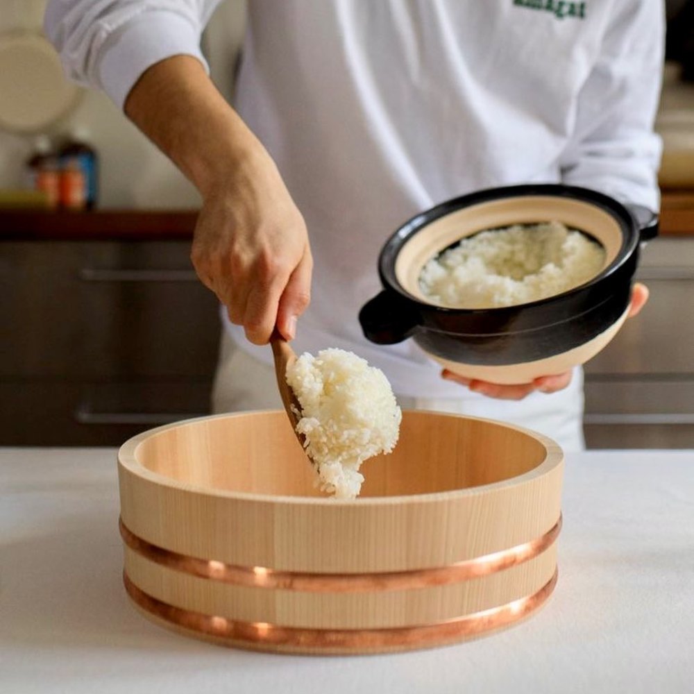 SUSHI OKE - Plat pour riz à sushi 🍣Plat large à fond plat en bois, cerclé de cuivre, permettant la préparation du riz à sushi. Aussi appelé hantai ou hangiri, il permet de réguler l'humidité du riz.SHIMIZU MOKUZAI réalise ces sushi oke dans la plus pure tradition, en bois local de Kiso Sawara hautement résistant à l'eau et durable. Le bois est sélectionné et coupé sur place puis travaillé par un artisan afin d'obtenir une surface lisse et plate.Lorsque vous vinaigrez le riz, l'humidité du riz doit être maitrisé. Sans l'usage de sushi oke, vous risquez d'obtenir un riz pâteux. L'effet du bois et un geste délicat vous permettra d'obtenir un riz vinaigré bien aéré et au doux parfum boisé.À retrouver en ligne et en boutique 📍©️photo : @thesocialfood#sushioke #nagatanien #nagatanien_donabe #donabe #maisongodillot #thesocialfood #hangiri #hangirisushi